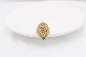 Dettaglio ravvicinato dell'anello dorato maschera indiana con intarsio in turchese verde