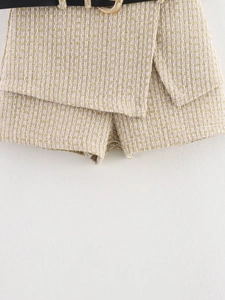 Detailed macro view of beige tweed skort with gold metallic threads and black belt