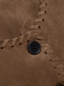 Vue détaillée du tissu en daim marron avec points de croix tissés main et boutons noirs