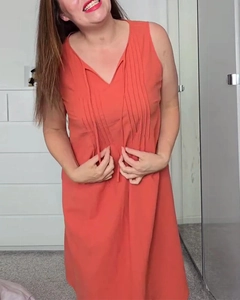 Detail of coral orange V-neck sleeveless dress featuring elegant vertical pleats