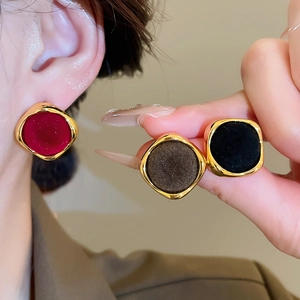 Detail of square flocked velvet earrings in wine red, dark brown and black with gold plating