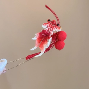 Detail view of red koi fish hair clip with embroidery and soft pom-poms on golden pin