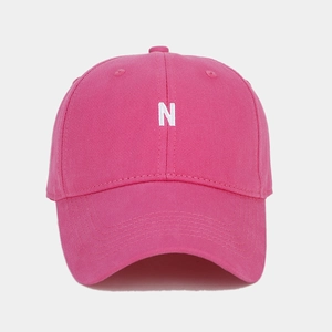 Detail of rose pink baseball cap featuring white N letter embroidery and cotton texture