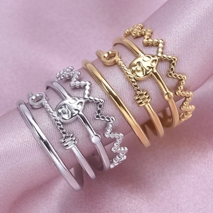 Detail of vintage gold and silver rings with crown and skull designs on pink satin