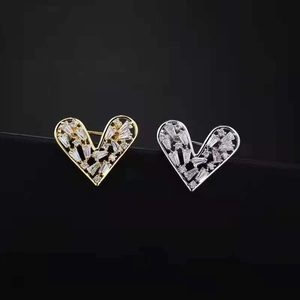Elegant gold and silver heart brooches with pave zircon stones on black background