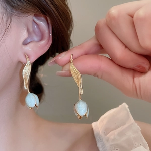 Detail of tulip earrings with gold leaves and blue oil-dripping petals on model