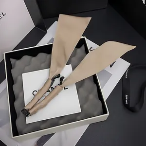 Dettaglio dell'elegante fermaglio a banana in seta beige con lunghi nastri regalo