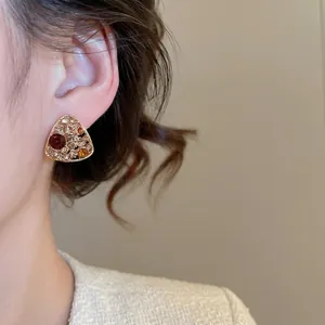 Vintage gold triangle stud earrings with multi-colored crystals worn by a female model
