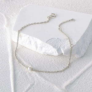 Macro detail of 925 sterling silver chain bracelet with a single natural white pearl bead