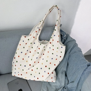 Detailed view of cream canvas tote bag with colorful polka dots on a sofa with tablet