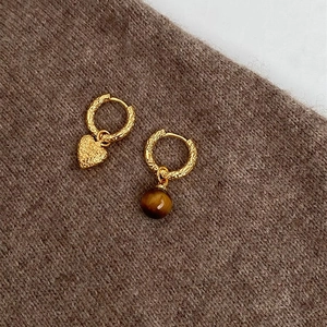 Detail of vintage gold plated hoop earrings with heart and brown bead charms on knit fabric