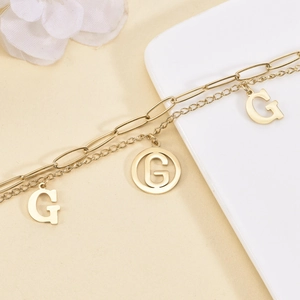 Double-layer gold titanium steel bracelet featuring hollow G-letter pendants and paperclip chain