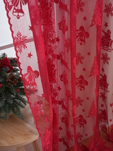 Détail du rideau de Noël en dentelle rouge avec motifs de rennes et flocons de neige