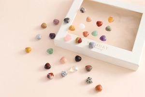 Mixed heart-shaped polished crystal stones in various colors on a peach gift box