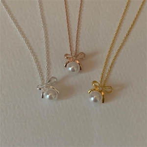 Bowknot pearl necklaces displayed in silver, gold, and rose gold finishes in a flat lay