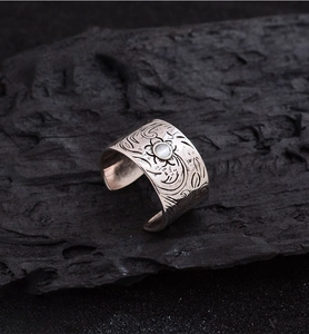 Detail of wide vintage silver ring with floral engraving and white cat eye stone