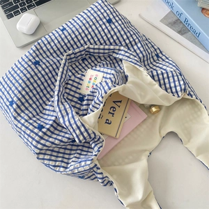 Détail du tote bag en toile à carreaux bleus avec broderie florale et accessoires