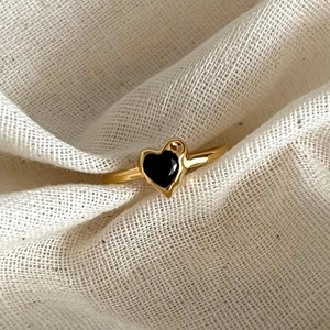 Elegant 925 sterling silver heart ring with black zircon stone on textured white fabric