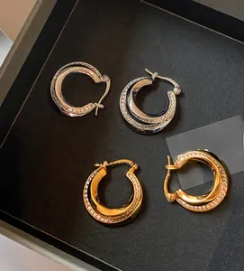 Detail view of gold and silver double-layered twist hoop earrings with pavé diamonds