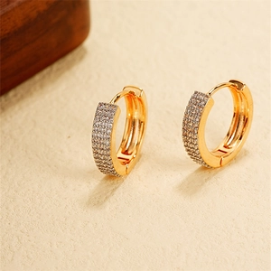Close-up of gold-plated U-shaped huggie earrings with shimmering cubic zirconia stones