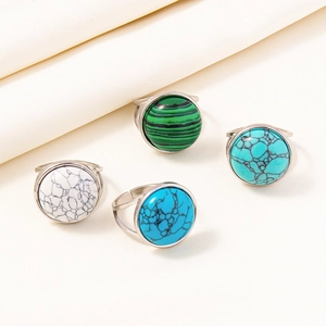 Detail of adjustable silver rings featuring turquoise and malachite stones on fabric
