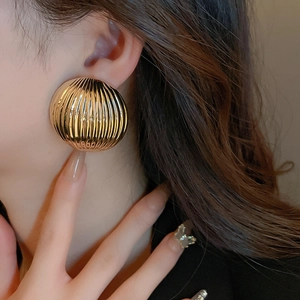 Macro shot of gold semi-sphere stud earring with vertical striped metal texture