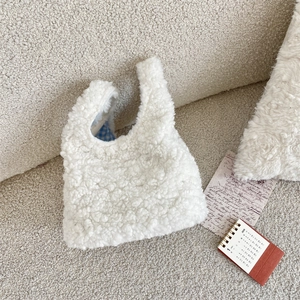 Close-up of white plush handbag with blue checkered lining and soft faux fur texture