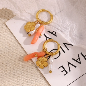 Close-up of gold flower earrings with white pearls and coral-toned pendant details
