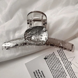 Transparent resin hair claw clip with a silver metal plate inlay on white fabric