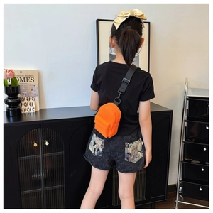 Detail of a mini orange nylon crossbody bag with black adjustable strap and zippers