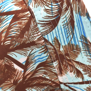 Macro detail showing tropical palm print and reinforced stitching on a reversible bucket hat