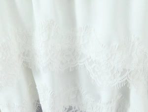 Gros plan sur la dentelle florale blanche avec bordure en cils d'une robe