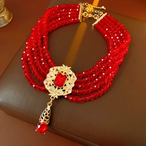 Macro detail of a five-layer vintage red beaded necklace with ornate golden centerpiece