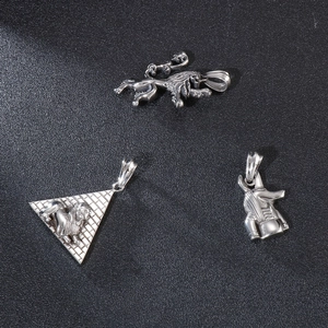 Silver pyramid and lion head stainless steel pendants on a black leather background