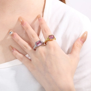 Detail of twisted rope band rings with pink rectangular stones on person's hand