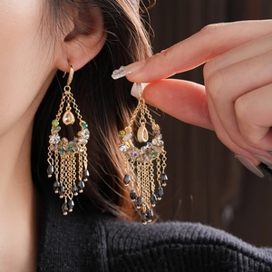 Detailed view of bohemian gold tassel earrings with green zircon and black water drop beads