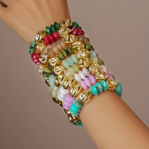 Close-up of stacked acrylic beaded bracelets with gold accents and colorful round beads