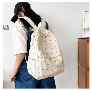 Side view of cream floral backpack with pink patterns showing capacity and straps