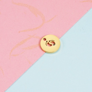 Close-up of golden stainless steel round pendant with hollowed-out footprints design