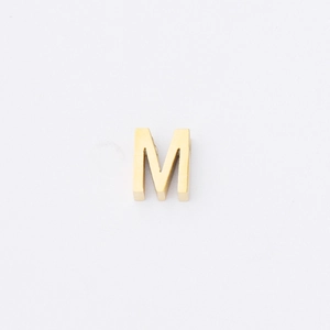 Detailed macro view of a 1.8mm gold-plated stainless steel letter M bead with mirror finish