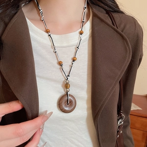 Detail of wooden round pendant necklace with brown beads on a professional model