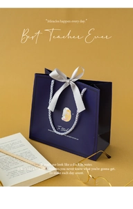 Detail of dark blue gift bag for teachers with silver ribbons and academic props