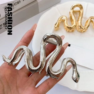 Macro shot of stylish gold and silver snake-shaped metal hair claws with glossy finish