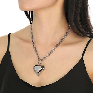 Asymmetric stainless steel necklace with hollow heart pendant worn by a model