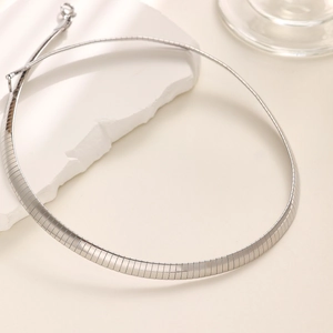 Detailed shot of polished silver omega chain necklace on a minimalist stone setting