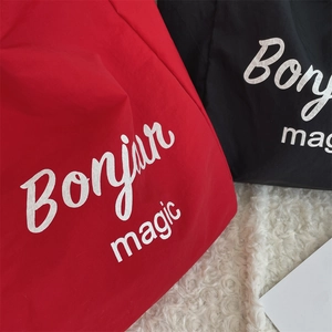Detailed close-up of red and black tote bags with Bonjour magic print on fleece