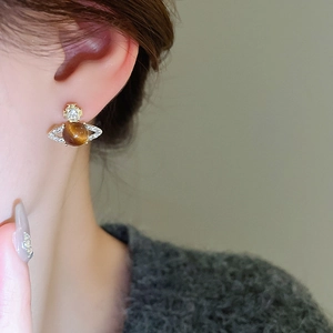 Detail of planet-shaped stud earring with brown cat eye stone and pavé zircons on ear