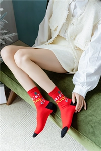 Détail de chaussettes de Noël rouges avec lettrage tricoté et motifs de flocons verts