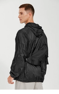 Detailed side view of black functional chest bag on model with adjustable strap and buckles