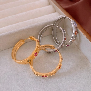 Detail of gold and silver flower hoop earrings with colorful zircon in a jewelry box